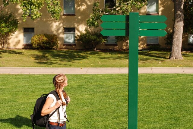 backpacker looking at signpost