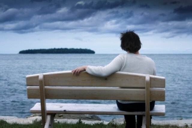 Man relaxing on bench looking out to sea